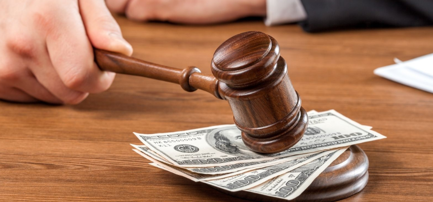 A judge's gavel strikes a pile of cash on a wooden table during a debt-recovery tribunal