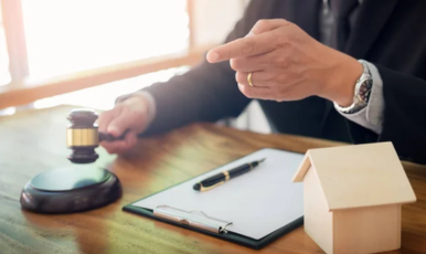 A gavel in the hand of a judge, targeting flaws in a house through legal scrutiny